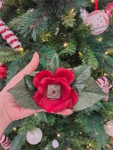 Pince à cheveux de couleur rouge avec en son centre un grand bouton en forme géometrique brun. Autour de la rose il y a des pétales vertes